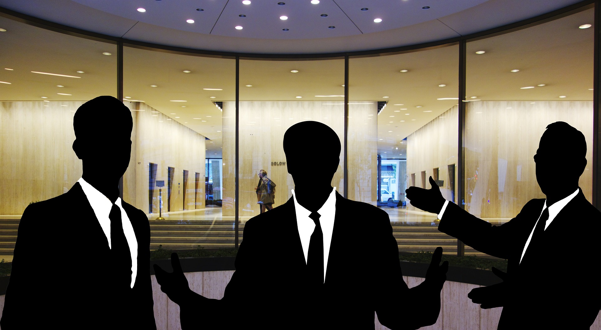 tři siluety mužů v prosklené hale